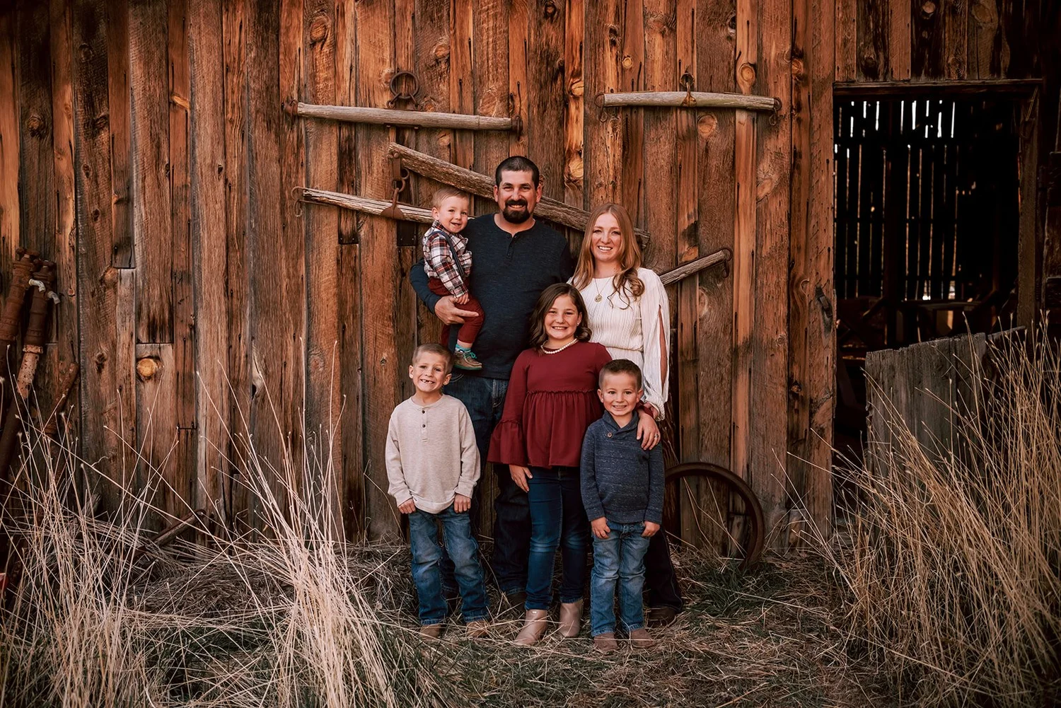 Sean and his wife with their four kids in front of the weathered wood of the old barn